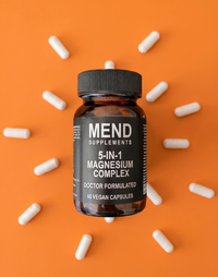 Mend 5-in-1 Magnesium Complex bottle on a bright orange background surrounded by capsules [card]
