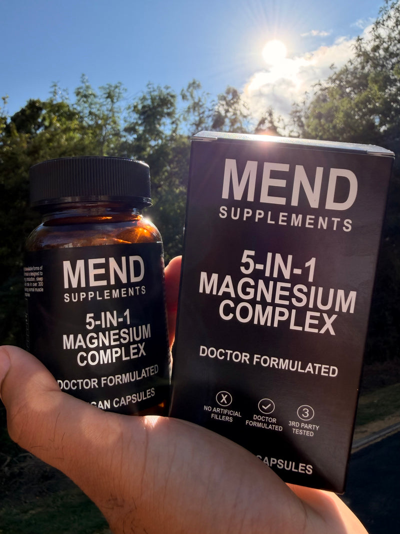 Hand holding the Mend Supplements 5-in-1 Magnesium Complex bottle and box outdoors in sunlight